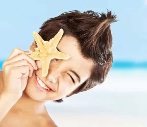 young boy smiling while holding starfish